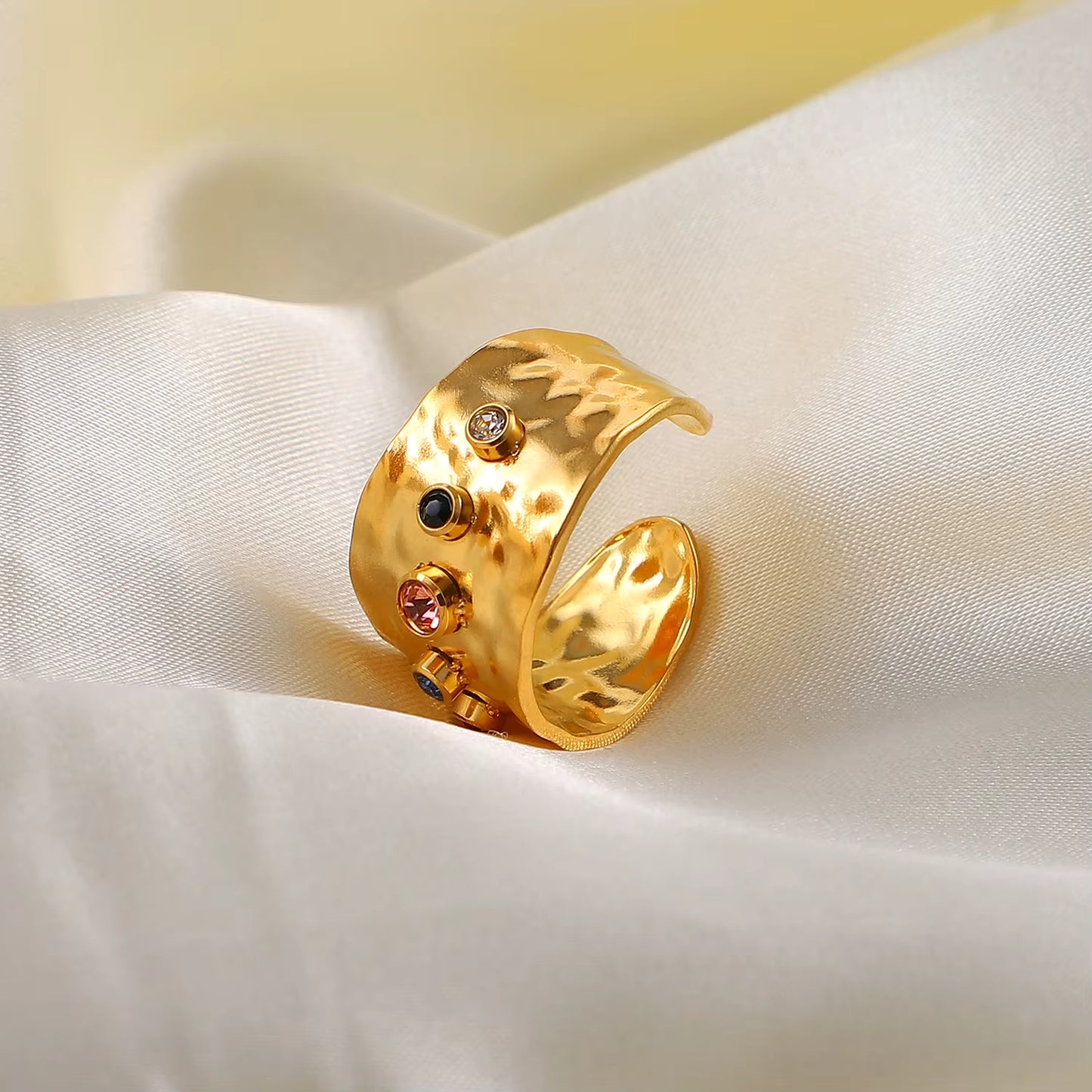 Gold ring with embedded stones on a white fabric background