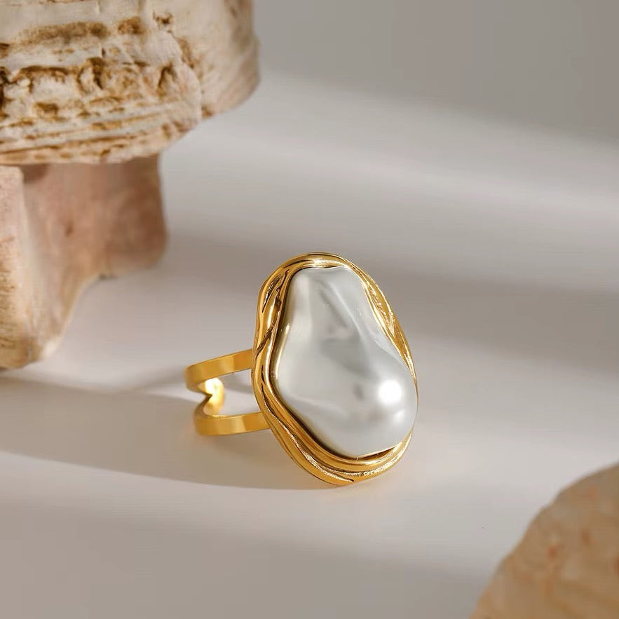 Gold ring with a large pearl on a neutral background