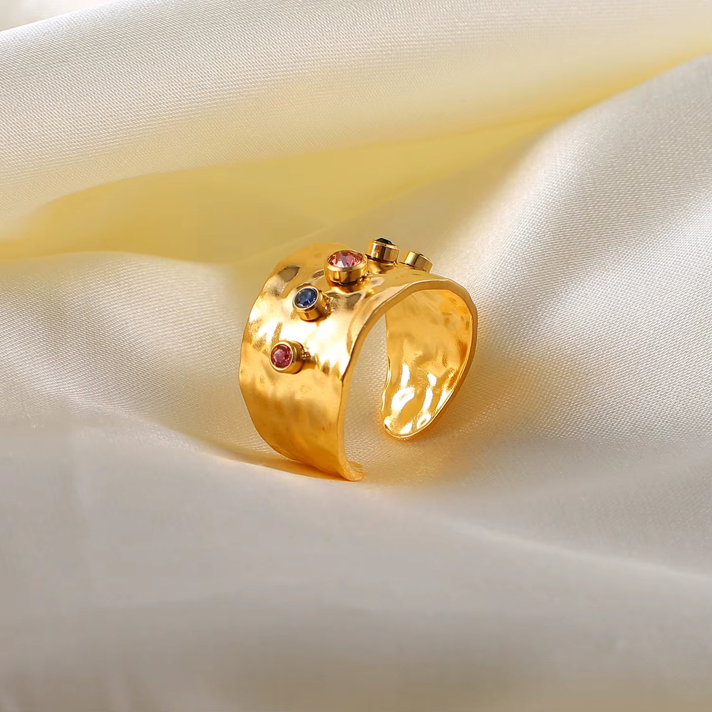 Gold ring with gemstones on a beige fabric background