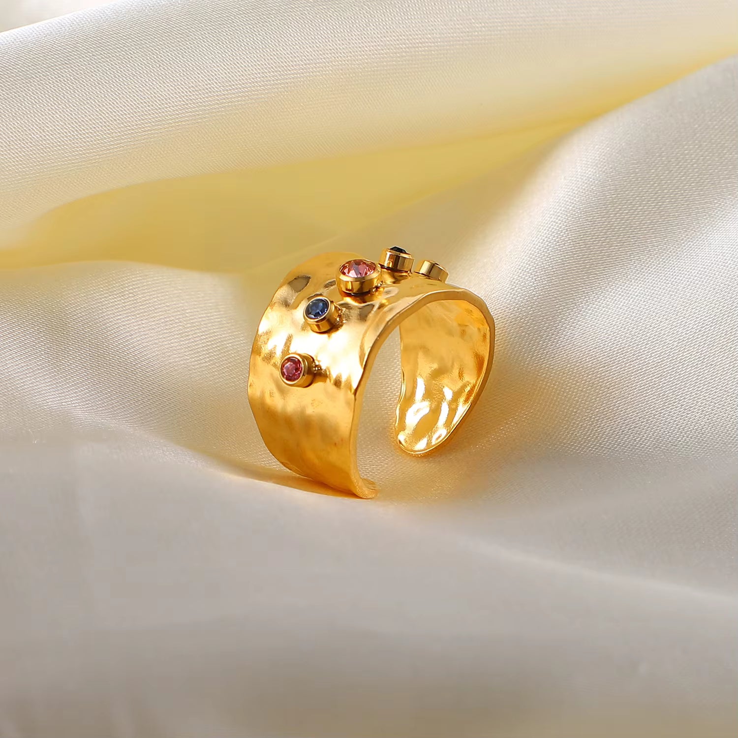 Gold ring with gemstones on a beige fabric background