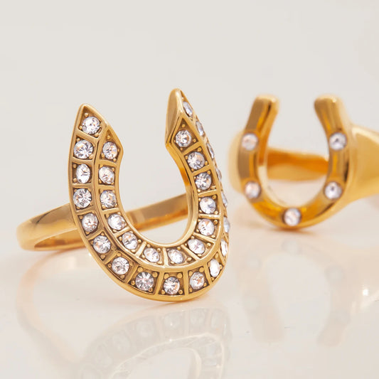 Gold horseshoe-shaped earrings with crystal embellishments on a light background