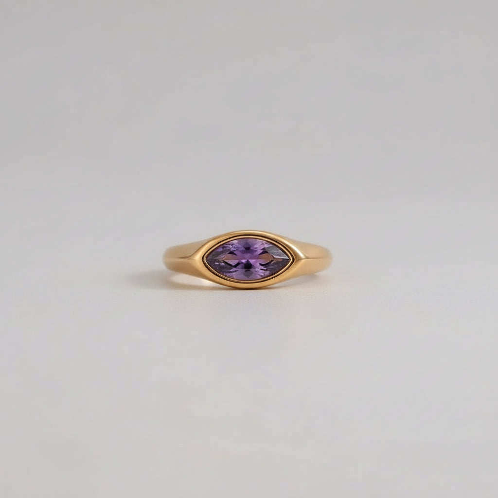 Gold ring with a purple gemstone on a light gray background